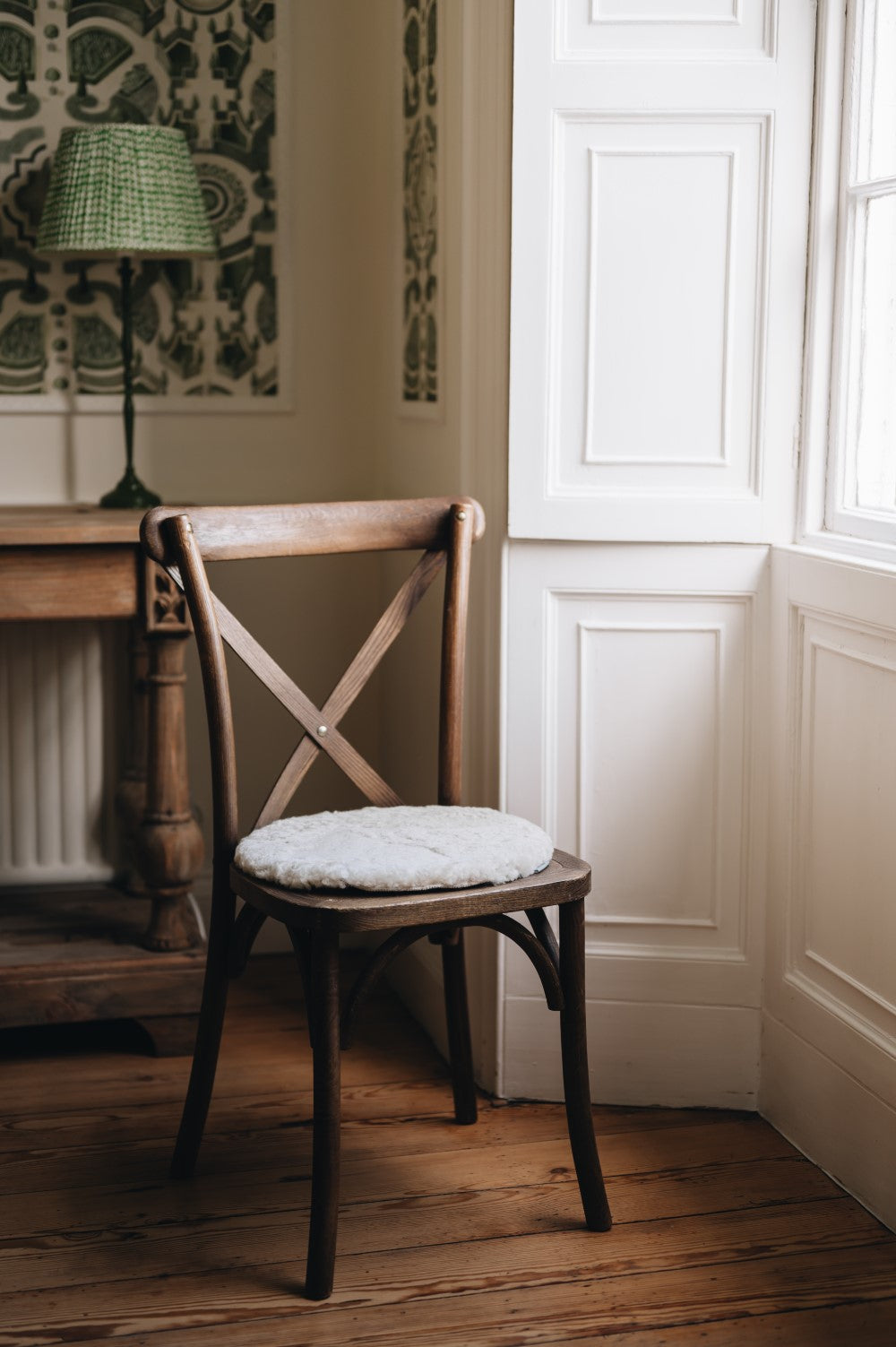 Oatmeal sheepskin round seat pad on wooden chair