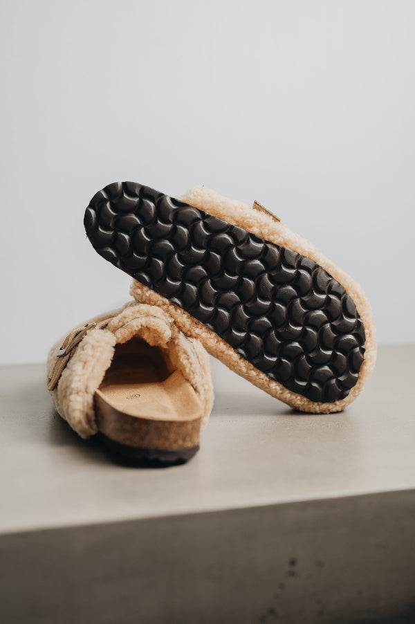 The patterned EVA sole of a curly sheepskin mule