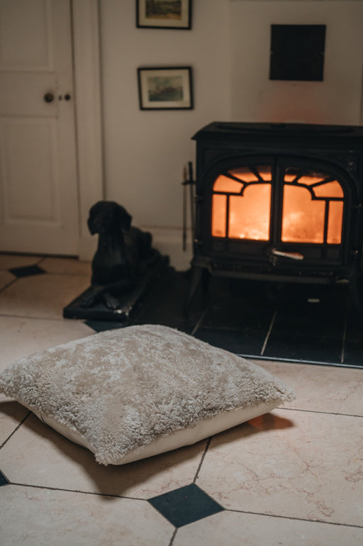 Big Sheepskin and leather backed Floor cushion. Infront of a fire in Oatmeal colour