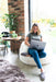 White Shorn Icelandic Sheepskin Bean Bag. Model sat cross legged on bean bag with computer.