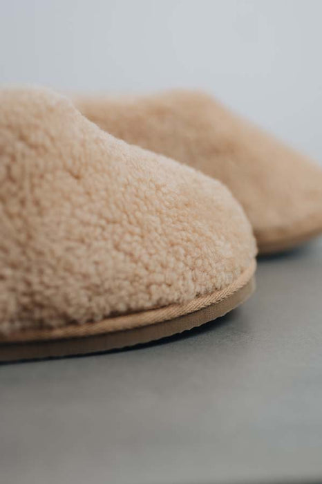 Close up of the toe post of a camel coloured curly merino sheepskin boot slipper.