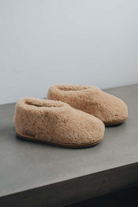 Side view of a camel coloured curly merino sheepskin boot slipper.