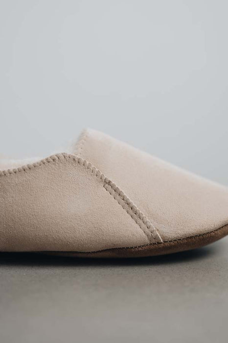 Close up view of Grace, a light soft-soled sheepskin slipper, showing the detail of the side stitching.