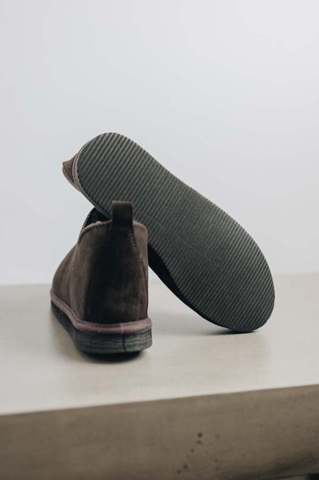 Close up of dark brown coloured ankle-high sheepskin slipper showing the ribbed underside of the PVA sole