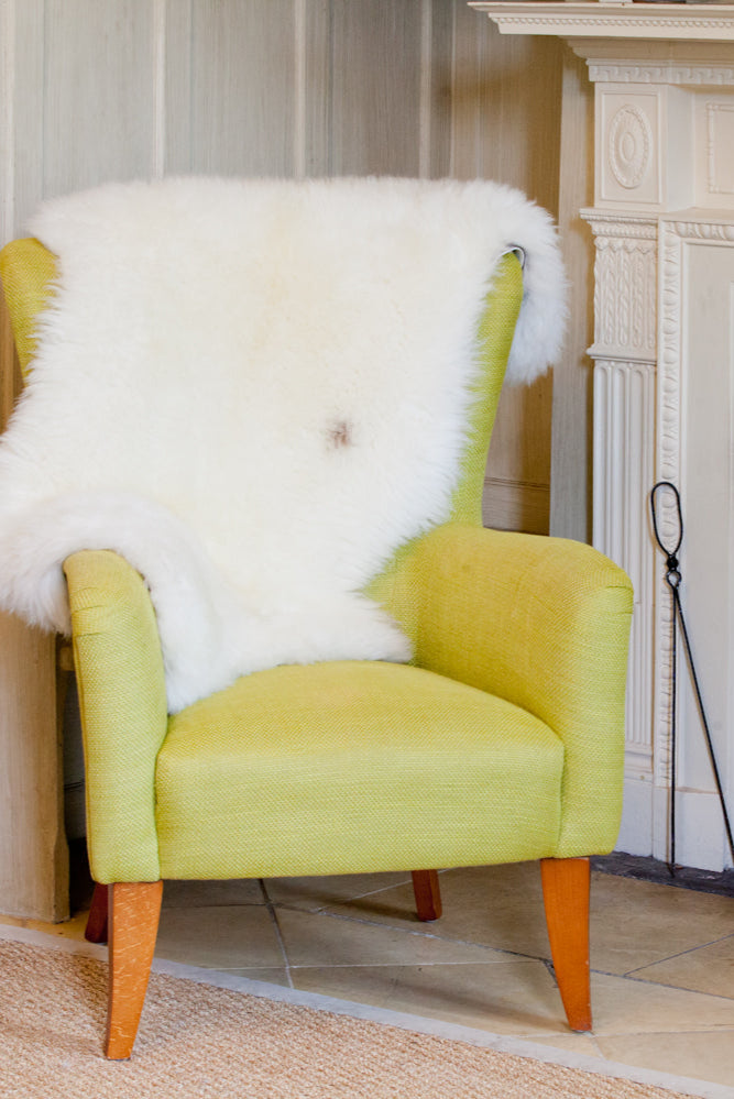 Fireside  appeal - All Natural British Sheepskin Rugs - Natural white nestled in the back of a high backed  chair by the fire