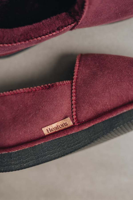 Close up of Bordeaux coloured loafer style sheepskin slipper with natural cork label showing the Heatons brand