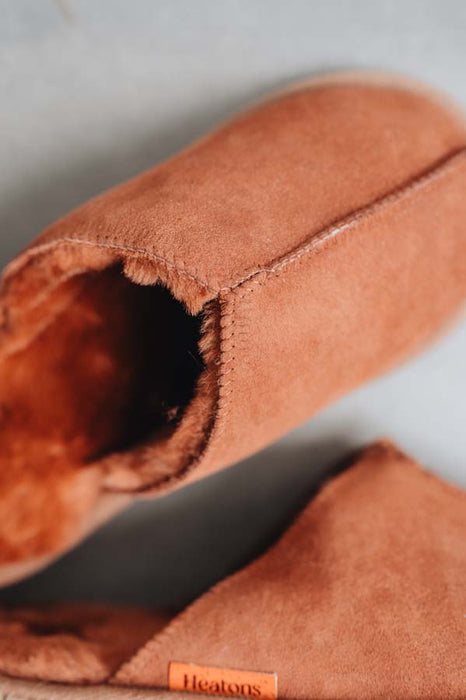 Close up of rust coloured slip on style sheepskin slipper with orange cork label showing the Heatons brand
