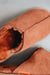 Close up of rust coloured slip on style sheepskin slipper with orange cork label showing the Heatons brand
