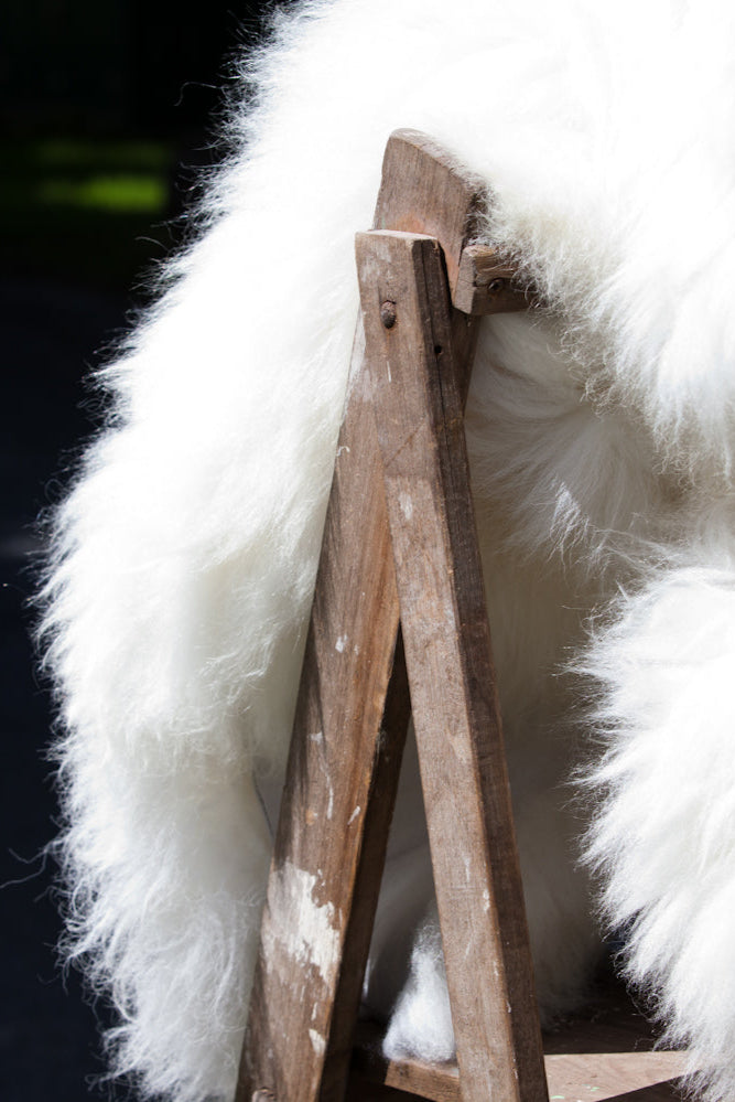 Natural white sheepskin rug draped over wooden post