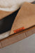 Close up of tan coloured slip on style sheepskin slipper with orange cork label showing the Heatons brand