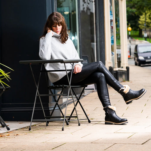Model wearing Smilla Black leather and Sheepskin Boots, sitting in front of coffee shop.