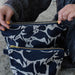 Model unzipping Large and Small Navy Blue Abstract Small Creatures Patterned Blästa Henriët Linen Wash Bag. Includes gold zipper for easy opening.