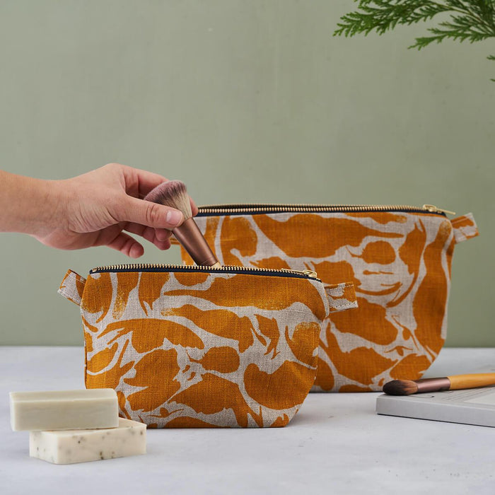 Model putting makeup brush in Small Yellow Creatures Abstract Pattern Wash Bag, with zip. Linen Wash Bag by Blästa Henriët. Larger size in back of photograph.