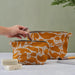 Model putting makeup brush in Small Yellow Creatures Abstract Pattern Wash Bag, with zip. Linen Wash Bag by Blästa Henriët. Larger size in back of photograph.