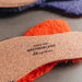 Orange AW22 colour Sheepskin Children's Cuttable Insoles. Cut to size. Close Up of Cork Cuttable back with Westmorland Sheepskins Logo.