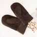 Brown Children's Sheepskin Mittens, displayed next to Ellie May designed postcard.