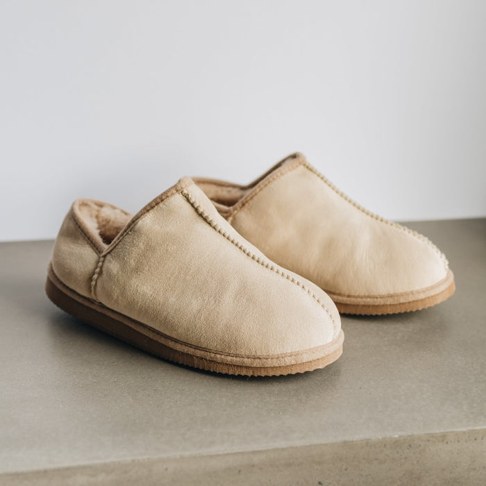 Side view of CADI Vanilla Sheepskin Unisex Slipper, designed by Westmorland Sheepskins. Features a small branded cork tag sewn into outer trim.
