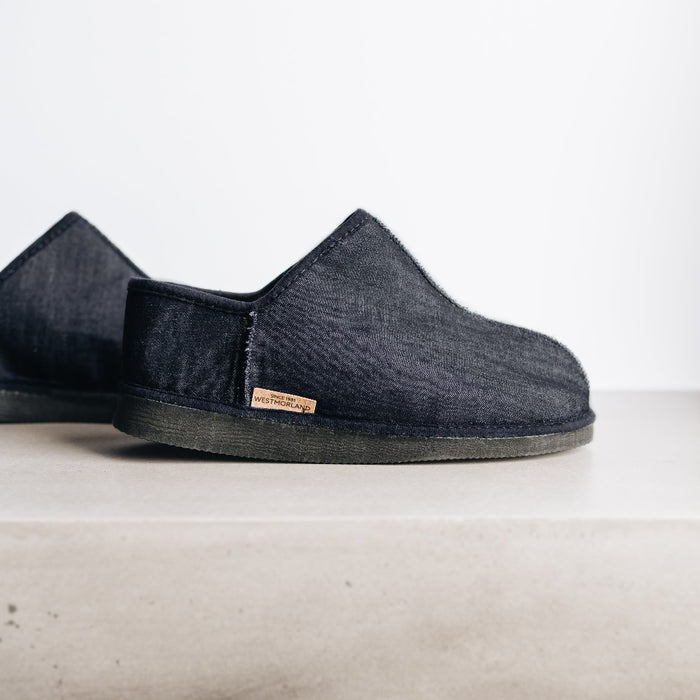 Side view of CADI Navy Denim and Sheepskin Men's Slipper, designed by Westmorland Sheepskins. Features a small branded cork tag sewn into outer trim.
