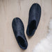 Top down view of CADI Navy Denim and Sheepskin Men's Slipper, designed by Westmorland Sheepskins. Features a small branded cork tag sewn into outer trim.