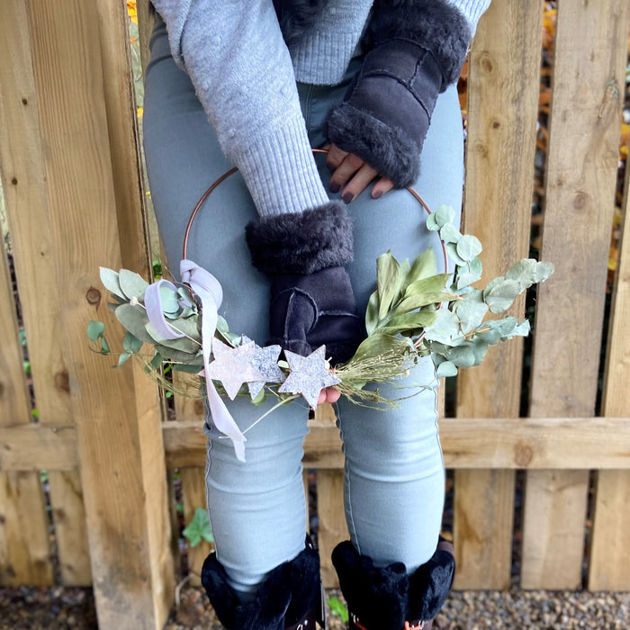 Grey Fingerless Sheepskin Mittens, worn by model holding wreath.
