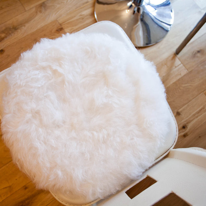 Round White Icelandic Sheepskin Seat pad, displayed on white chair.