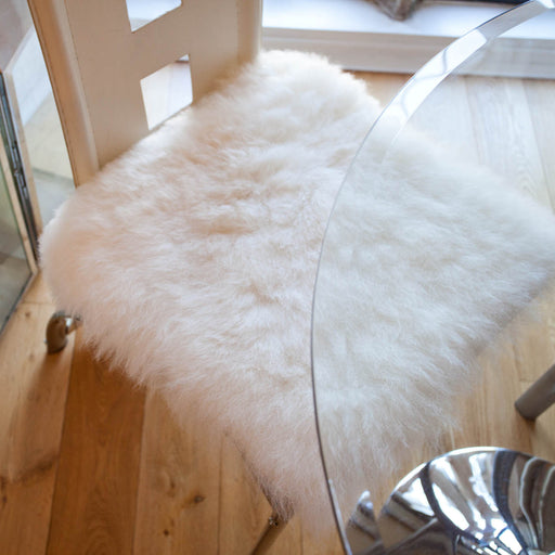 Square White Icelandic Sheepskin Seat Pad, displayed on white chair.