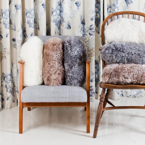 Icelandic Sheepskin Cushions in different colours, photographed on wooden chairs.
