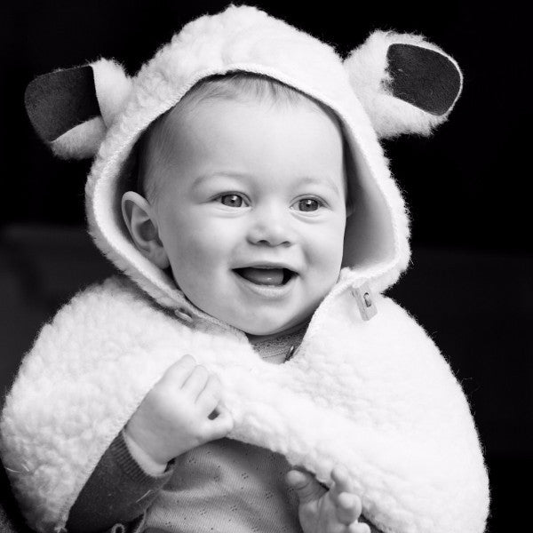Little Lamb Wool Baby cape, image shows baby smiling and wearing Baby cape.