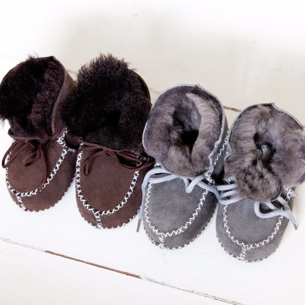 Laced toddle and baby booties and brown and grey. A sheepskin lined suede soft soled boot, with white stitching detailing and matching laces.