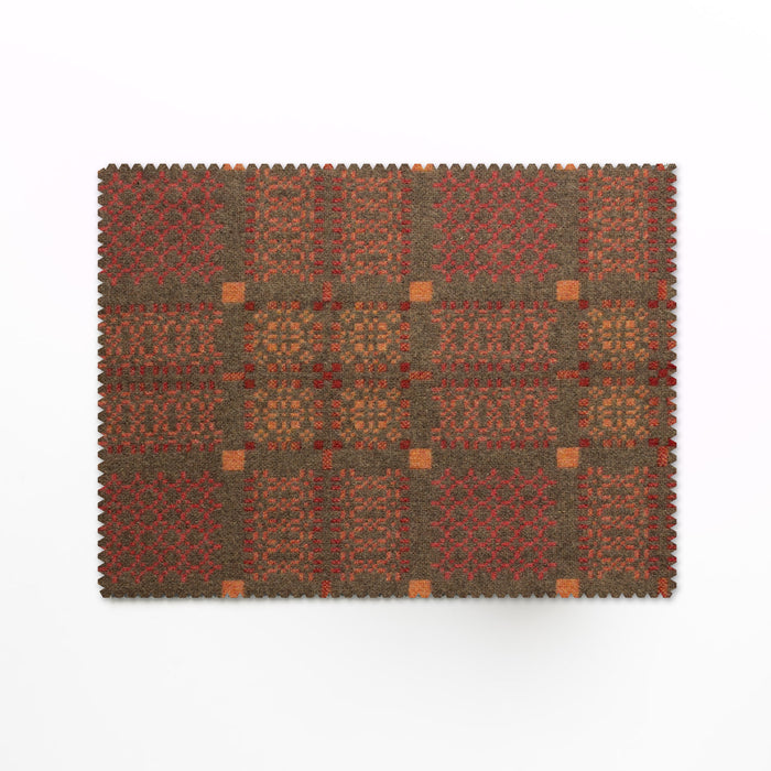 Melin Tregwynt Knot Garden Tablemats in Copper. Copper woven wool tablemats, features a repeating pattern in grey, light orange and rust red.