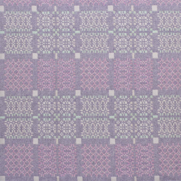 Lilac fabric for Purple Melin Tregwynt Knot Garden Woven Wool Throw. A light Lilac colour, with detail pattern in white, pale blue and purple.