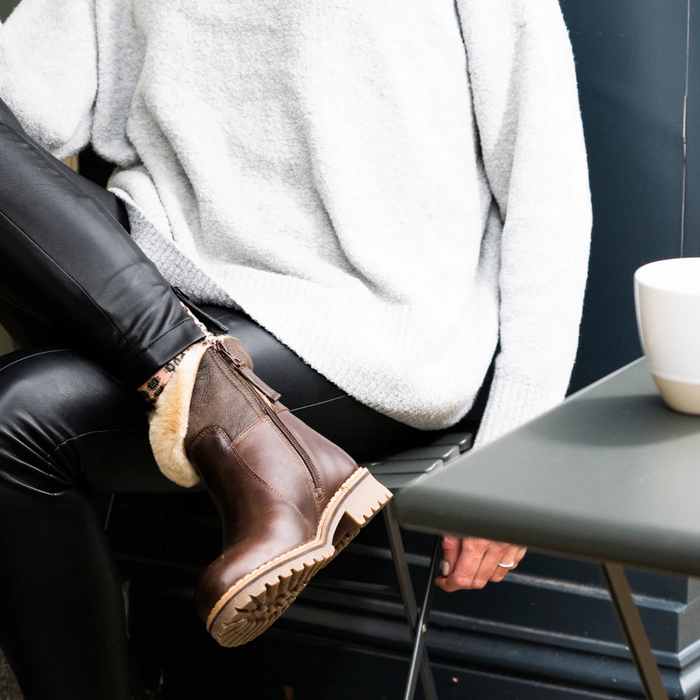 Model sat outside coffee shop, wearing brown Leather and Sheepskin Women's Boots, Smilla by Shepherd of sweden.